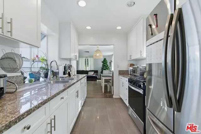 a kitchen with kitchen island granite countertop a sink stove and refrigerator