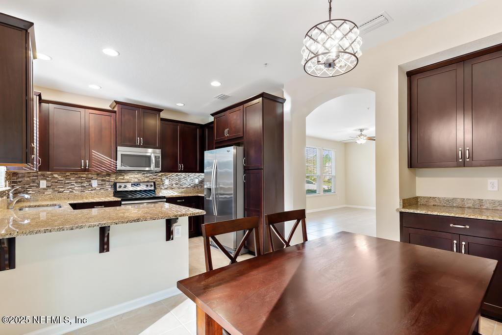 102 San Briso Way St. Augustine, FL 32092 - Photo 16 of 62 a kitchen with stainless steel appliances granite countertop a microwave a stove a refrigerator a sink a dining table and chairs with wooden floor