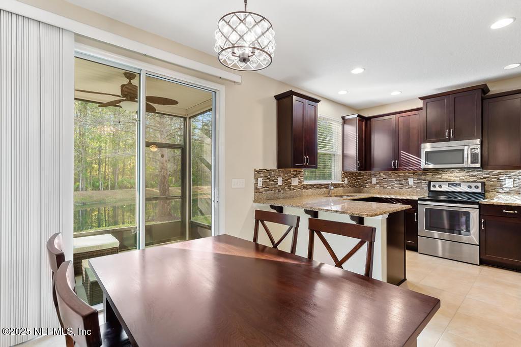 102 San Briso Way St. Augustine, FL 32092 - Photo 18 of 62 a view of kitchen with stainless steel appliances granite countertop a stove a sink a microwave dining table and chairs