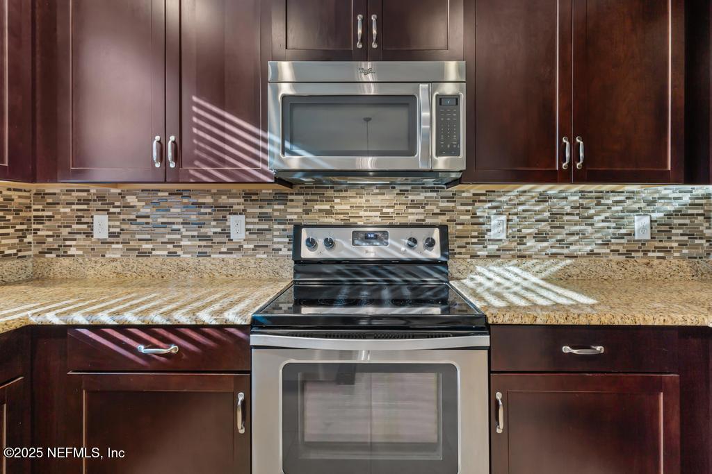 102 San Briso Way St. Augustine, FL 32092 - Photo 22 of 62 a kitchen with granite countertop a stove top oven microwave and cabinets