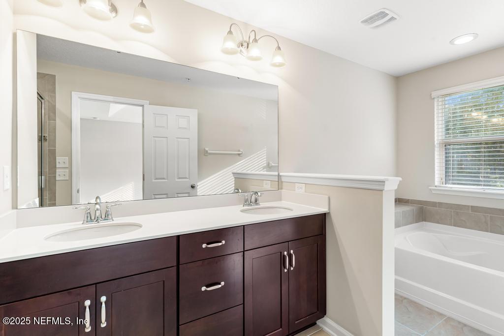 102 San Briso Way St. Augustine, FL 32092 - Photo 47 of 62 a bathroom with a sink double vanity granite tub shower and a mirror