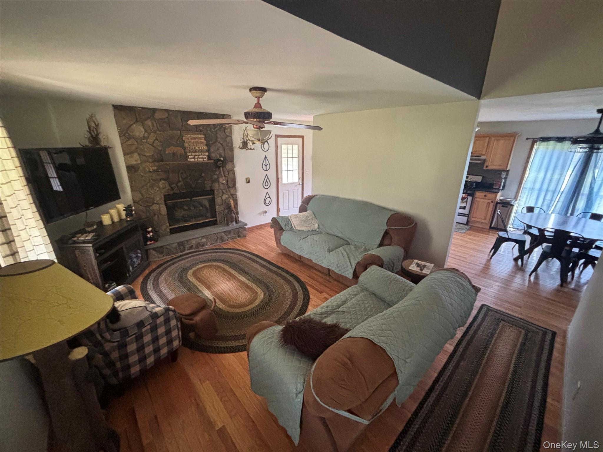 595 Hurd And Parks Road Swan Lake, NY 12783 - Photo 12 of 43 Living room featuring wood finished floors, a fireplace, and a ceiling fan