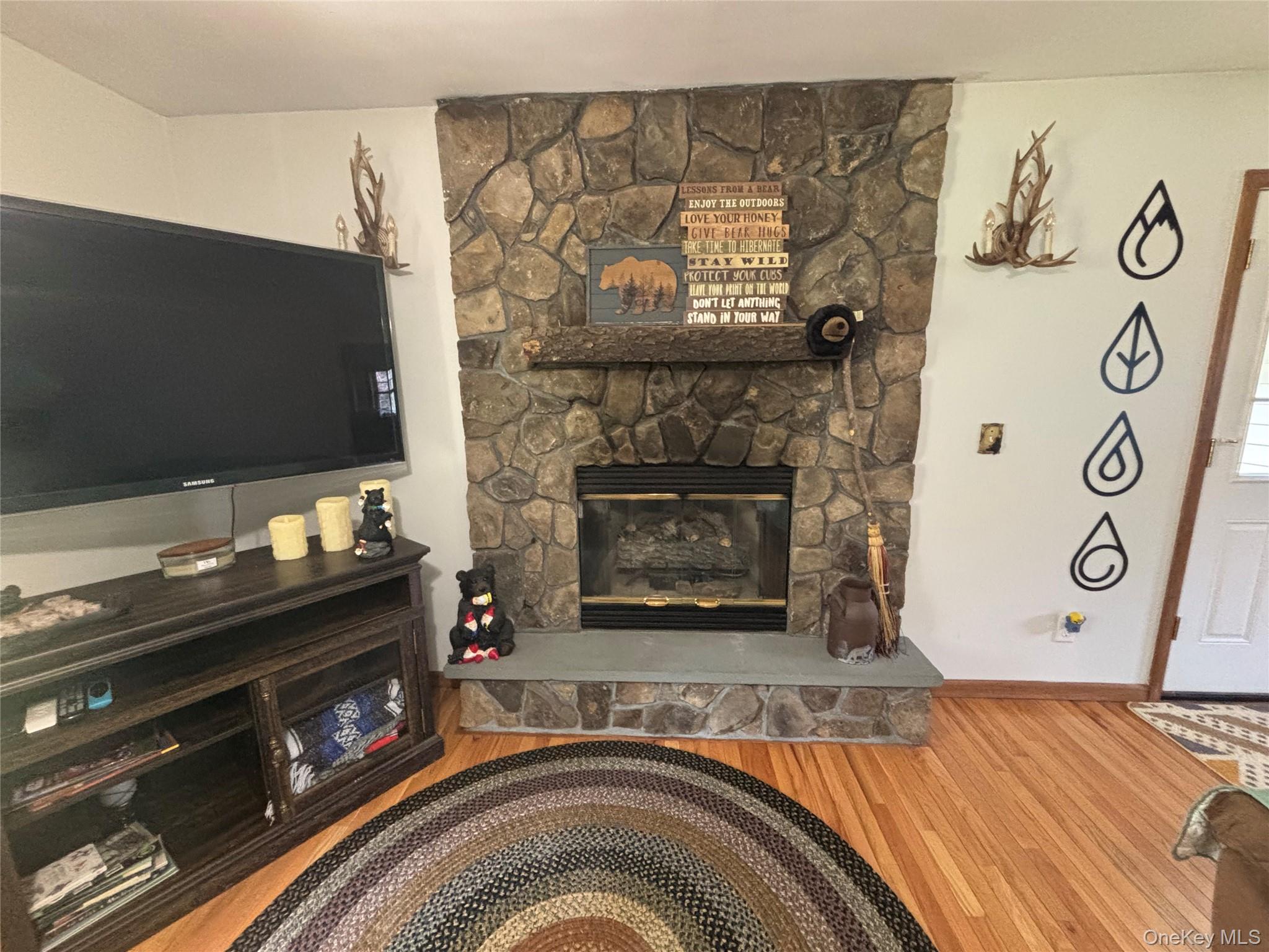595 Hurd And Parks Road Swan Lake, NY 12783 - Photo 14 of 43 Living room featuring a stone fireplace and wood finished floors