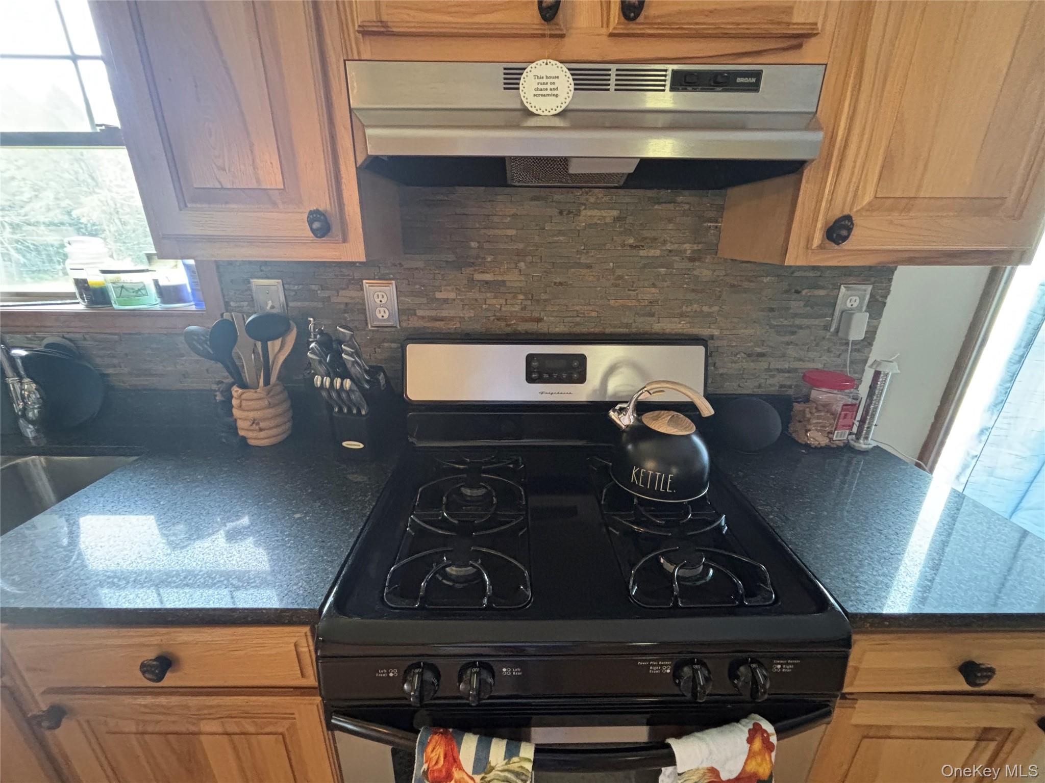 595 Hurd And Parks Road Swan Lake, NY 12783 - Photo 22 of 43 Kitchen with black range with gas cooktop, under cabinet range hood, tasteful backsplash, and dark countertops