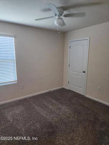 an empty room with a window and a fan