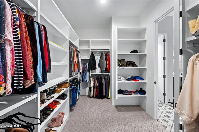 a view of walk in closet with clothes and shoes