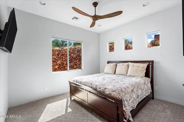 a bedroom with a bed a flat screen tv and a window