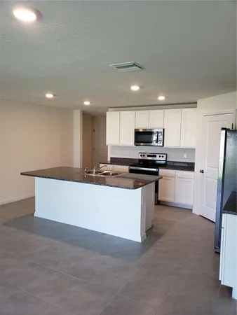 a kitchen with granite countertop white cabinets and stainless steel appliances