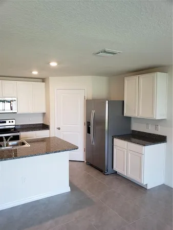 a kitchen with stainless steel appliances granite countertop a sink and a refrigerator