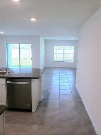a room with kitchen island granite countertop a stove a sink and a microwave