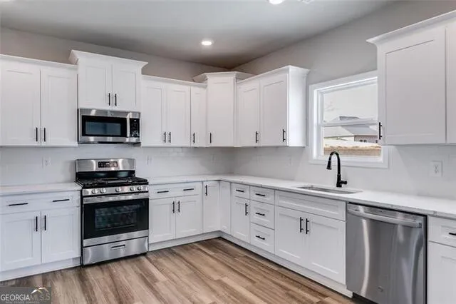 a kitchen with white cabinets and appliances