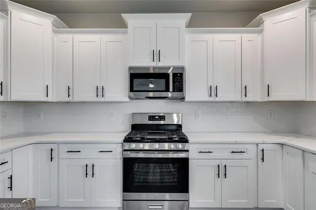 a kitchen with white cabinets and stainless steel appliances