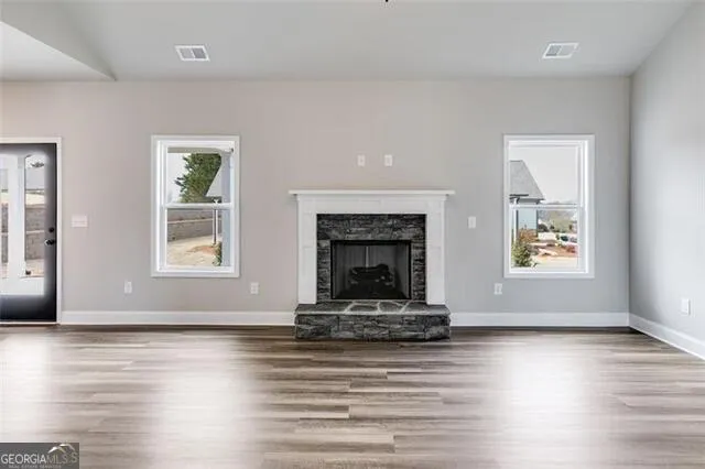 an empty room with window fireplace and wooden floor