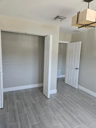 an empty room with wooden floor and a ceiling fan