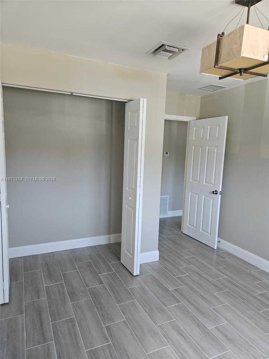 3906 Northwest 207 St Road, Unit 3906 Miami Gardens, FL 33055 - Photo 12 of 26 an empty room with wooden floor and a ceiling fan
