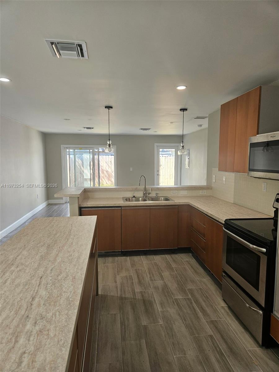 3906 Northwest 207 St Road, Unit 3906 Miami Gardens, FL 33055 - Photo 14 of 26 a large kitchen with a sink dishwasher a stove and a refrigerator with wooden floor