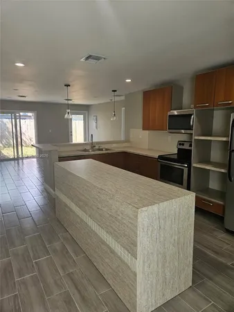 a large kitchen with kitchen island a sink stainless steel appliances and cabinets