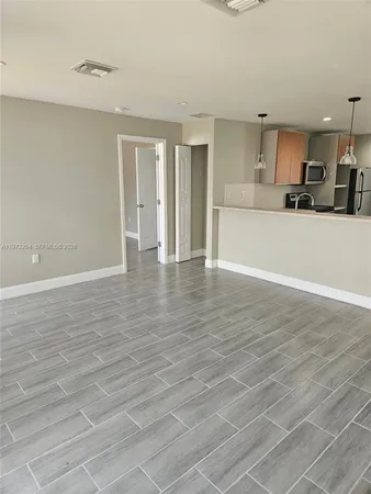 a view of large kitchen with stainless steel appliances wooden floor and large window
