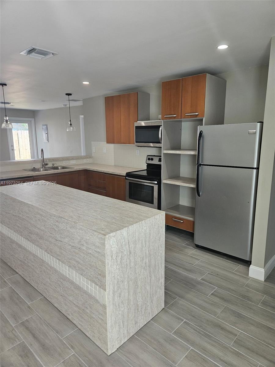3906 Northwest 207 St Road, Unit 3906 Miami Gardens, FL 33055 - Photo 5 of 26 a kitchen with stainless steel appliances granite countertop a refrigerator a stove a sink and a microwave oven on the wooden floor