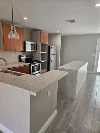 a kitchen with stainless steel appliances a sink a microwave a refrigerator and cabinets