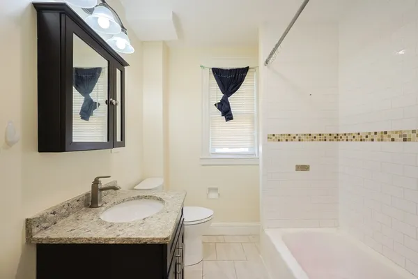 a bathroom with a granite countertop sink toilet and mirror