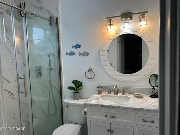 a bathroom with a granite countertop sink vanity mirror and toilet