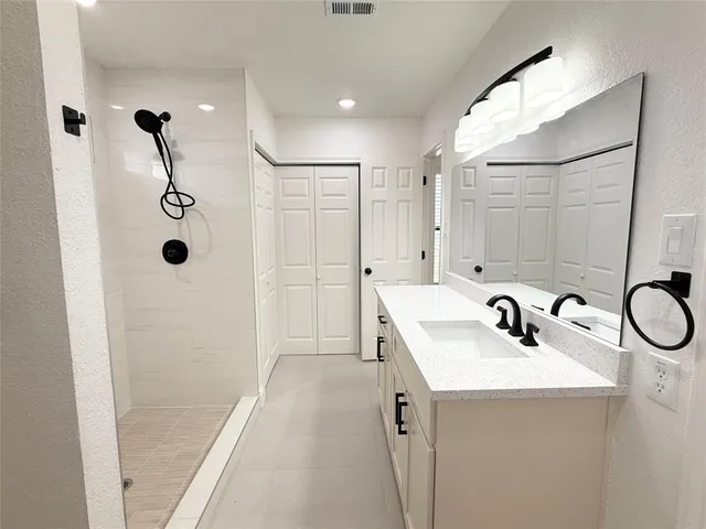 a bathroom with a sink a shower a mirror and vanity