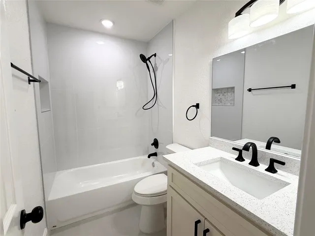 a bathroom with a granite countertop sink a toilet and shower