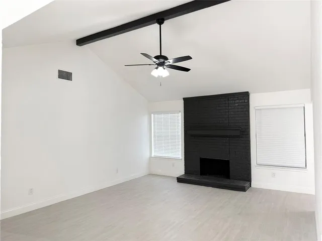 an empty room with fireplace and a ceiling fan
