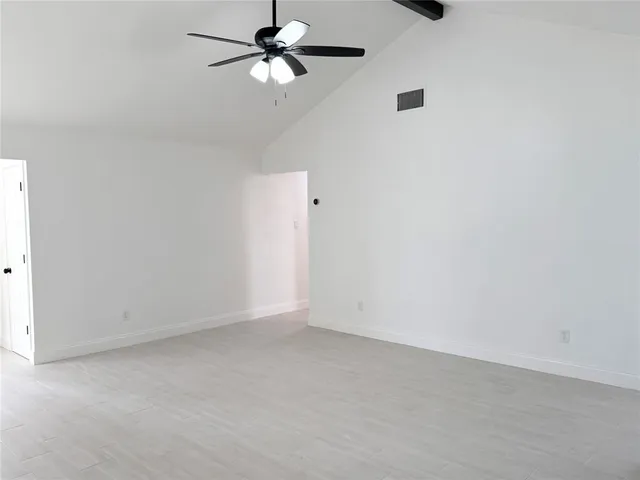 an empty room with a ceiling fan and a window