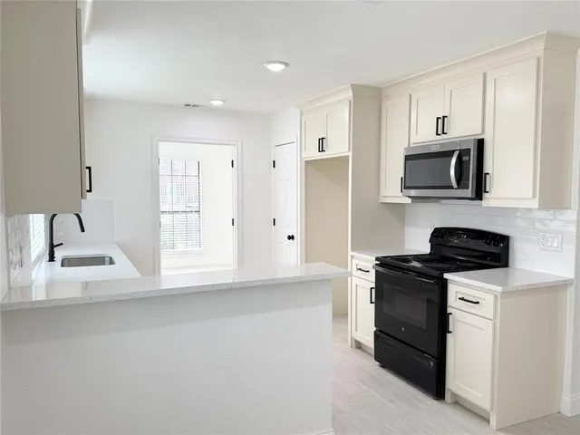 a kitchen with stainless steel appliances granite countertop a stove a sink and a microwave