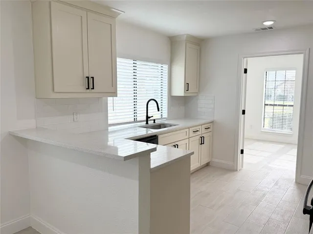 a kitchen with stainless steel appliances granite countertop a sink dishwasher a refrigerator and white cabinets