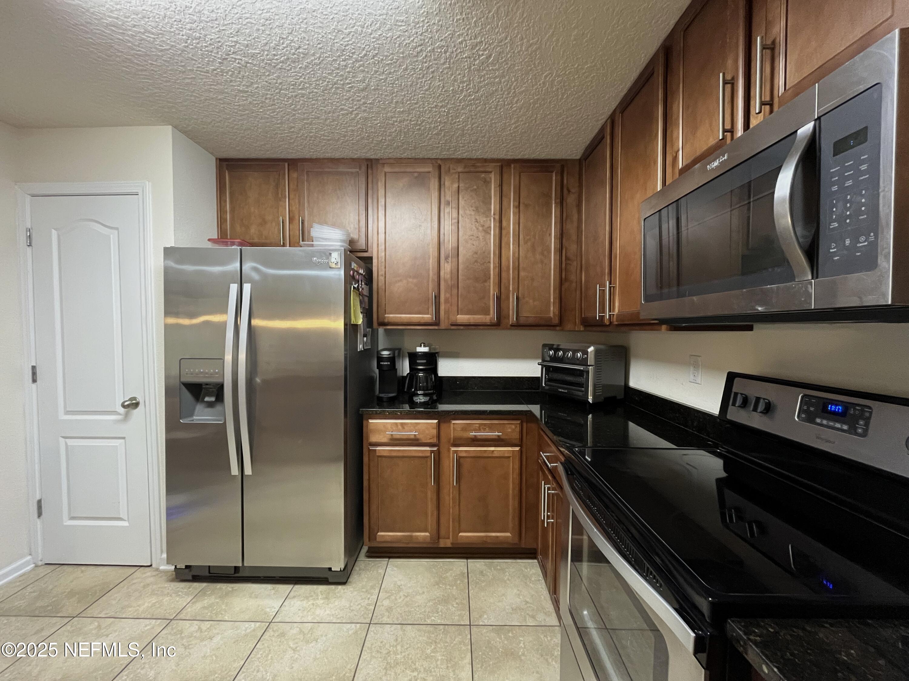 2103 Golden Lake Loop, Unit 2103 St. Augustine, FL 32084 - Photo 6 of 32 a kitchen with a refrigerator stove and microwave