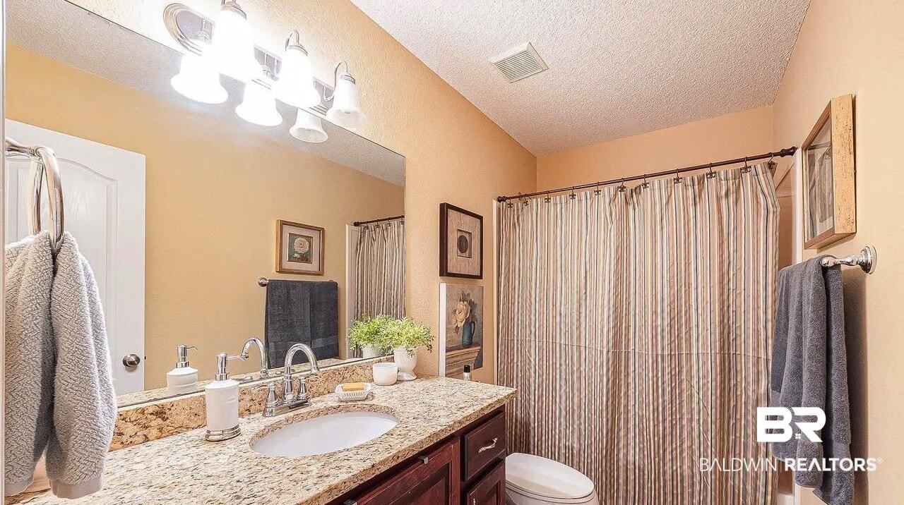 12230 Bromley Road Stapleton, AL 36578 - Photo 23 of 34 Bathroom featuring a textured ceiling, vanity, dark tile patterned floors, and a shower with shower curtain