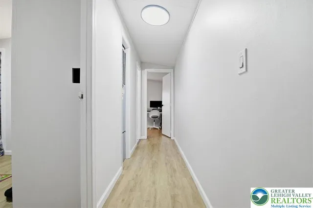 a room with a flat screen tv on the dresser and a wooden floor