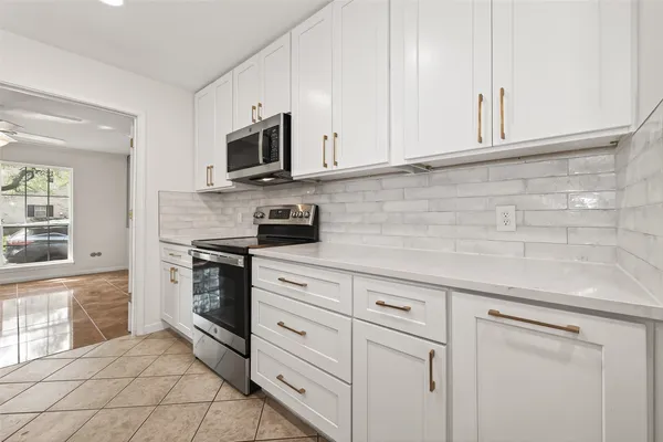 a kitchen with granite countertop white cabinets stainless steel appliances and a sink