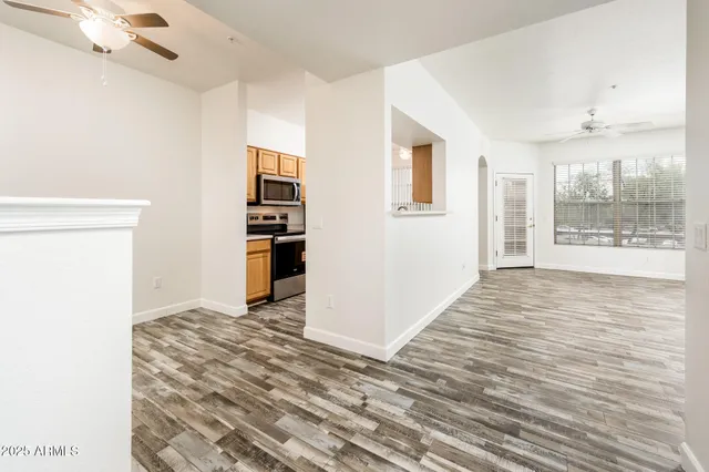 a view of an empty room with kitchen and window