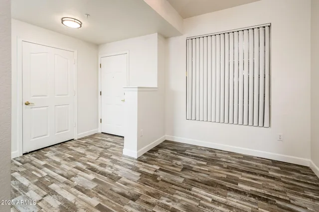 a view of an empty room with window and wooden floor