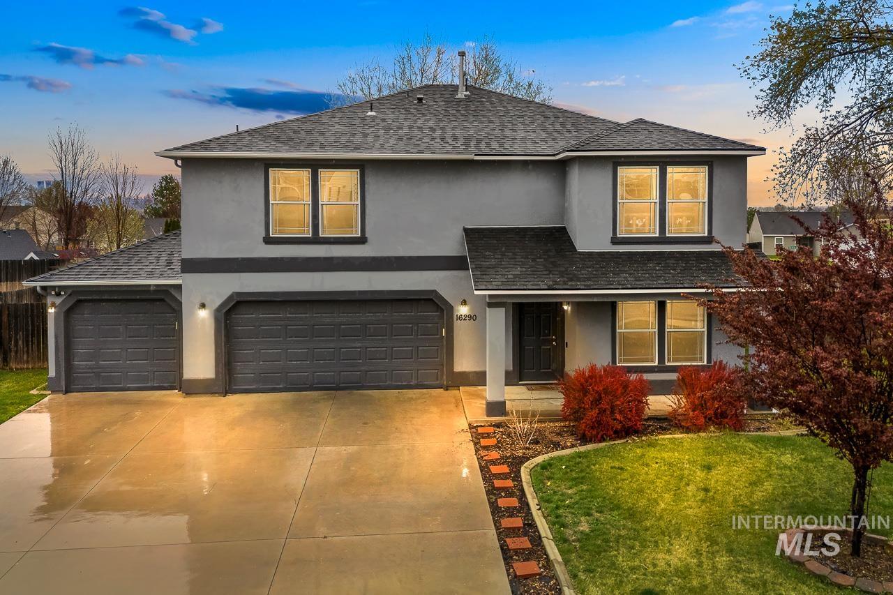 Traditional-style house with stucco siding, roof with shingles, and concrete driveway