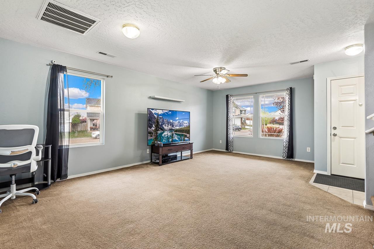 16290 Jewel Way Caldwell, ID 83607 - Photo 10 of 36 Living room with a textured ceiling, light carpet, a ceiling fan, and healthy amount of natural light