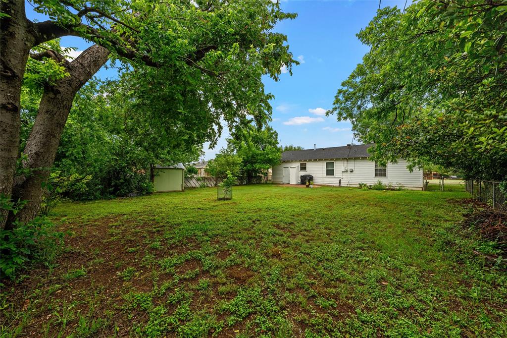 3904 North 21st A Street Waco, TX 76708 - Photo 22 of 26 Expansive backyard featuring mature trees, a detached storage shed, and a chain-link fence defining the property line