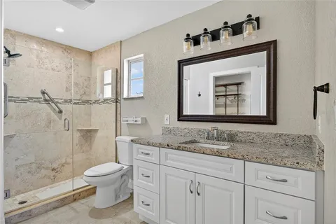 a bathroom with a granite countertop sink mirror vanity and toilet