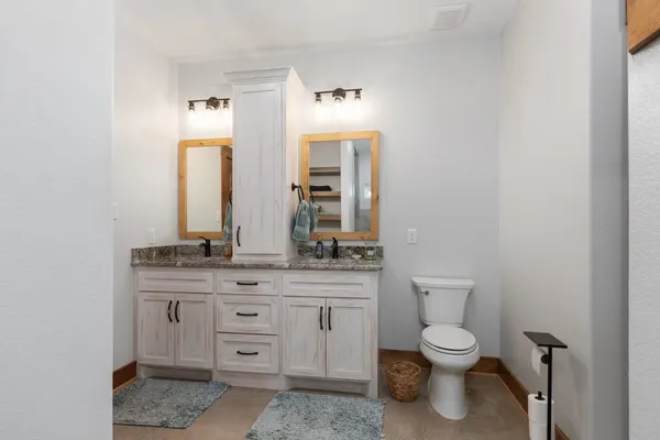 a spacious bathroom with a granite countertop toilet sink and mirror