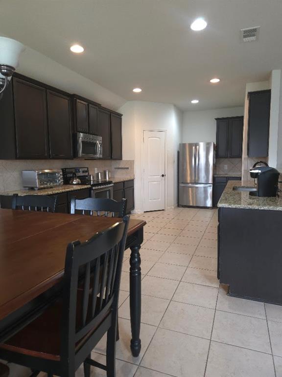 308 Kaylee Way Red Oak, TX 75154 - Photo 9 of 25 Kitchen featuring decorative backsplash, stainless steel appliances, light stone counters, light tile patterned floors, and recessed lighting