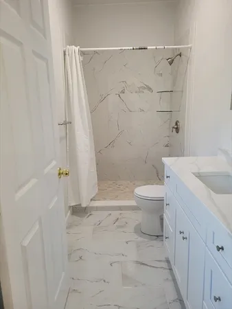 a bathroom with a granite countertop sink toilet and shower