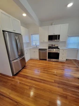 a kitchen with stainless steel appliances and wooden floor
