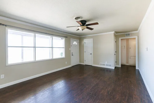 a view of an empty room with wooden floor and a window