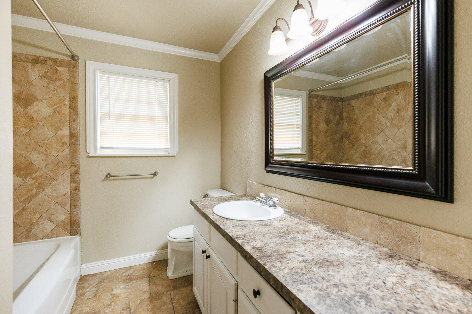 2505 52nd Street Lubbock, TX 79413 - Photo 32 of 37 a bathroom with a granite countertop sink toilet and mirror