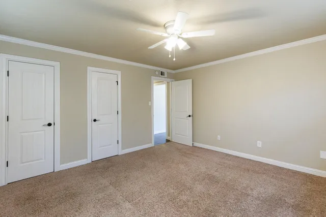 a view of an empty room with a chandelier fan