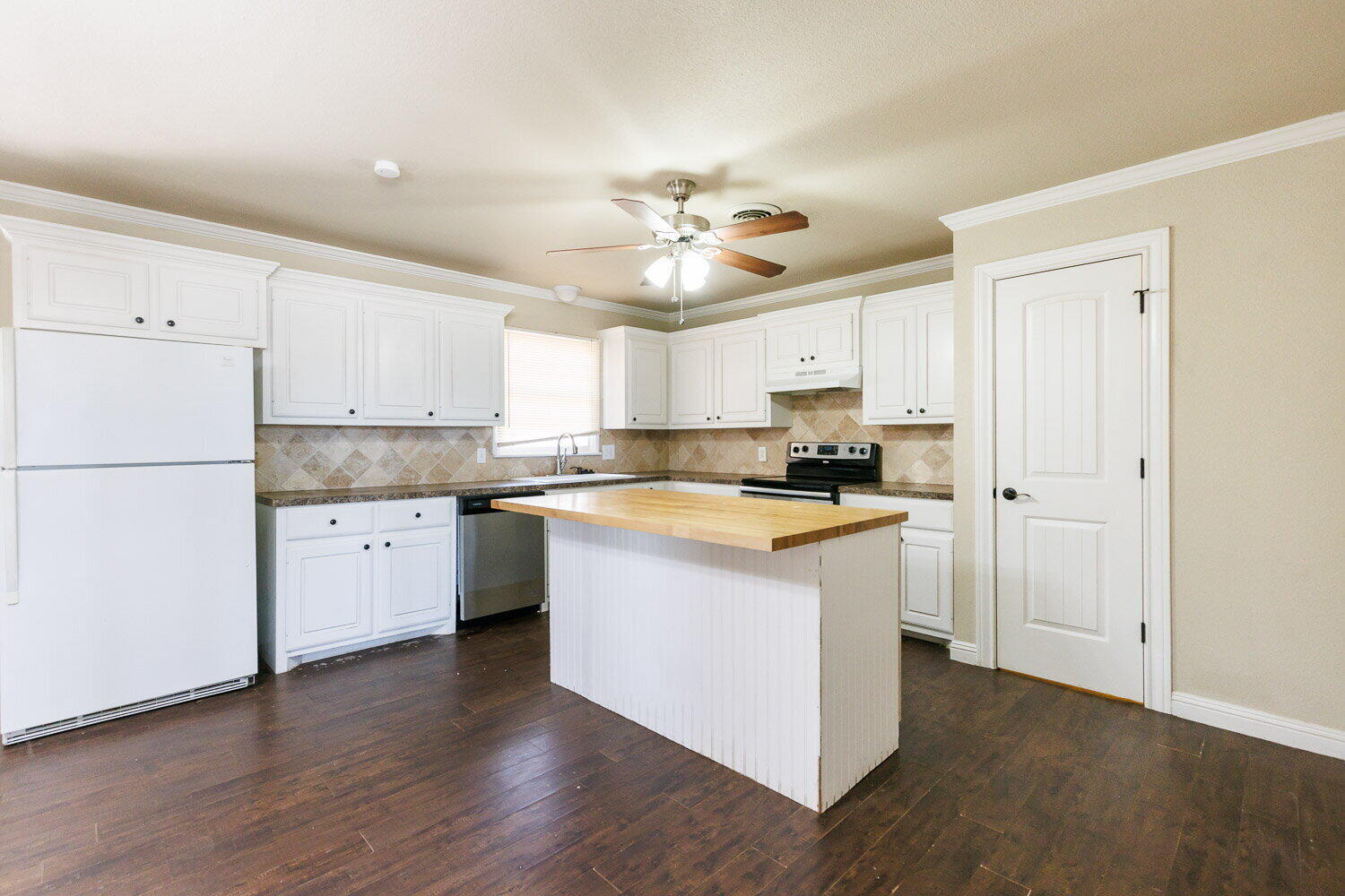 2505 52nd Street Lubbock, TX 79413 - Photo 6 of 37 a kitchen with stainless steel appliances granite countertop a refrigerator a stove a sink and white cabinets with wooden floor